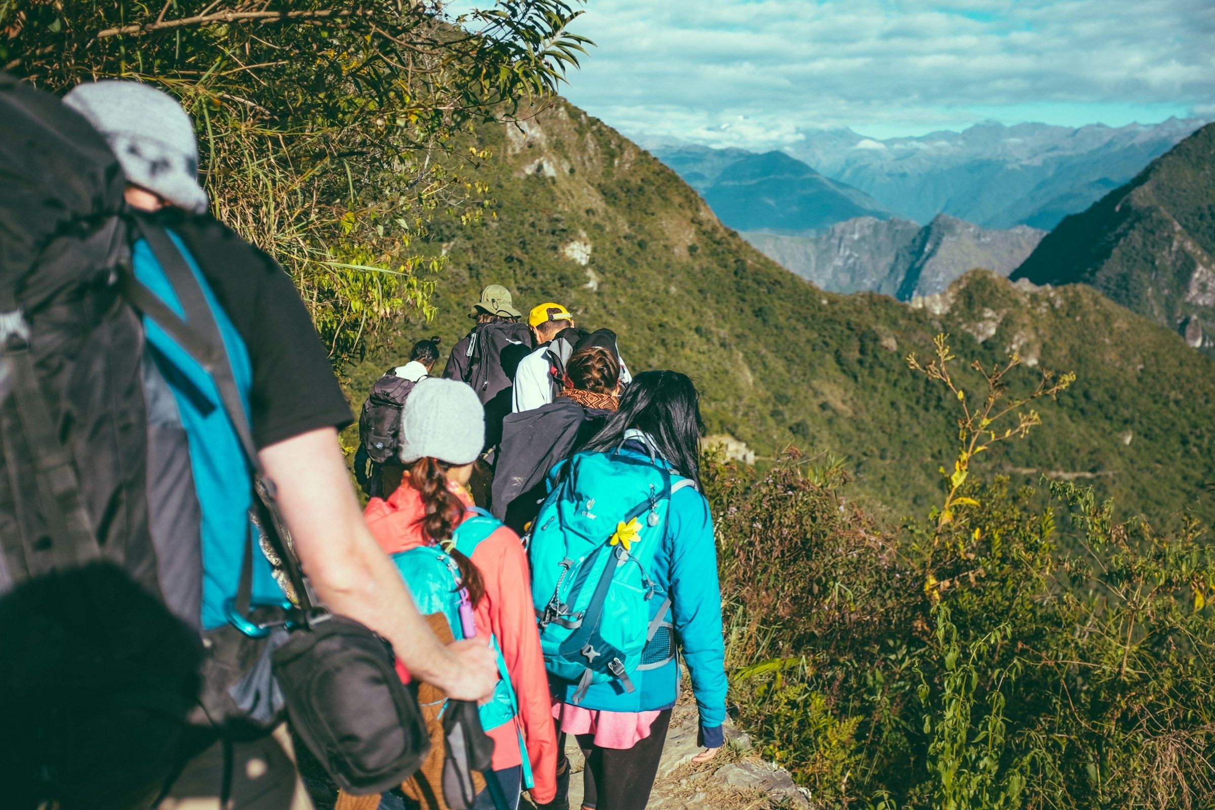 Grupo de mochileros de espaldas en un sendero de montaña en Cusco